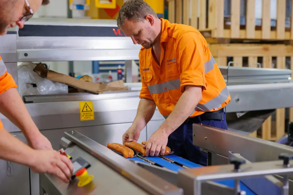 Two VACPAC technicians preparing food to test a vacuum packaging machine.