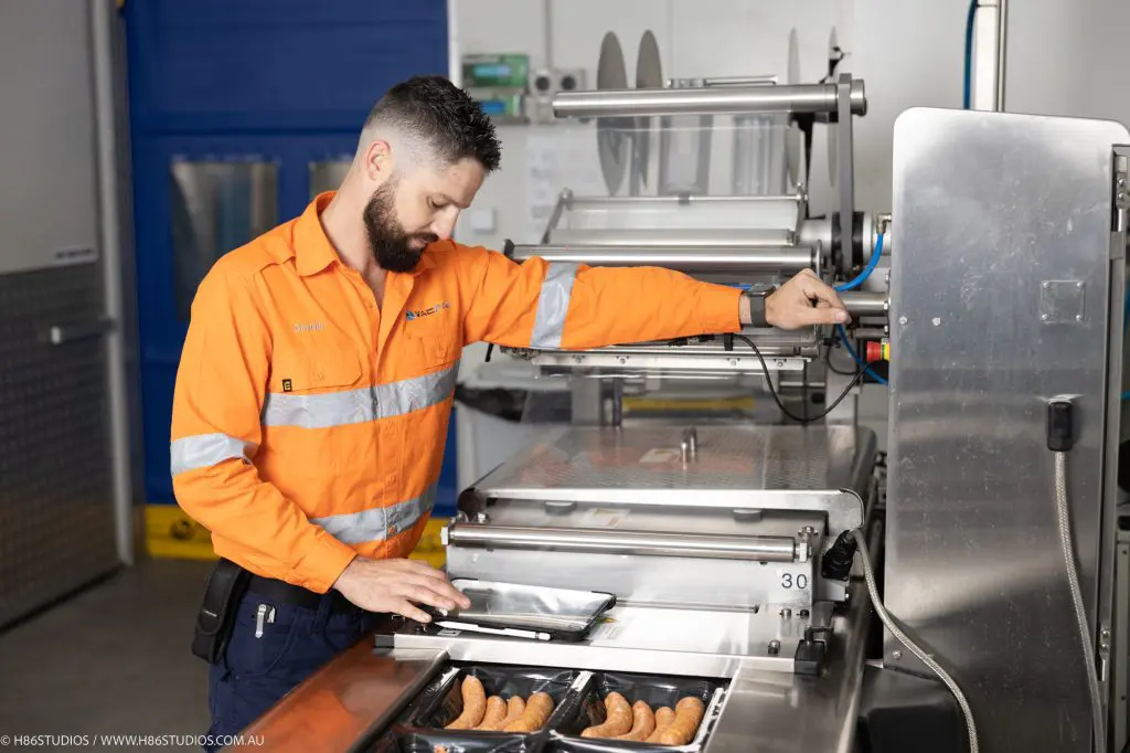 A VACPAC technician optimising the workflow of a vacuum packaging machine packaging line.