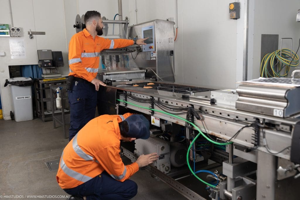 VACPAC engineering technicians inspecting and testing an automated food packaging machinery line to optimise facility efficiency and ensure secure sealing parameters.