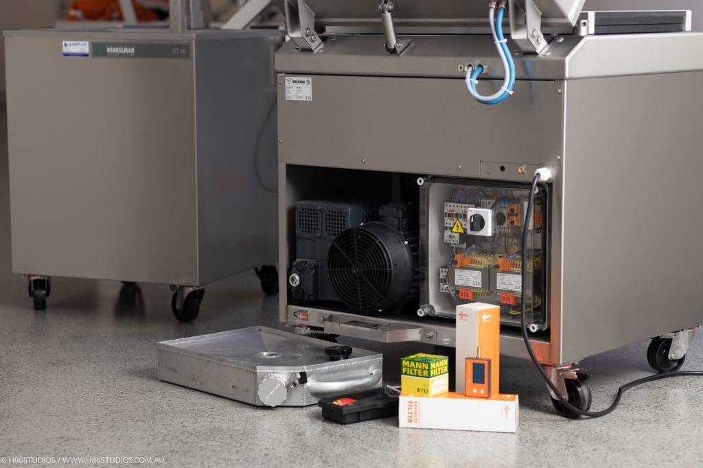 Internal mechanical components, an oil-rotary pump and filters exposed during a commercial vacuum sealer repair